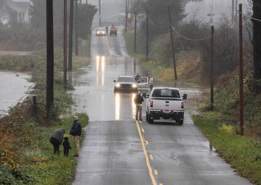 People try to navigate their cars along a flooded road near US 2 on Wednesday, Dec. 10, 2025 in Sultan, Washington. (Olivia Vanni / The Herald)