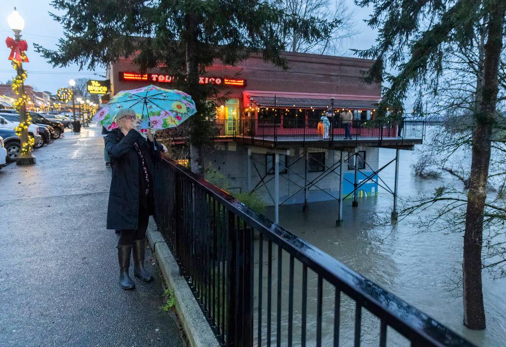 Lisa Ketcham pauses to take a video of the Snohomish River along First Street on Thursday, Dec. 11, 2025 in Snohomish, Washington. (Olivia Vanni / The Herald)