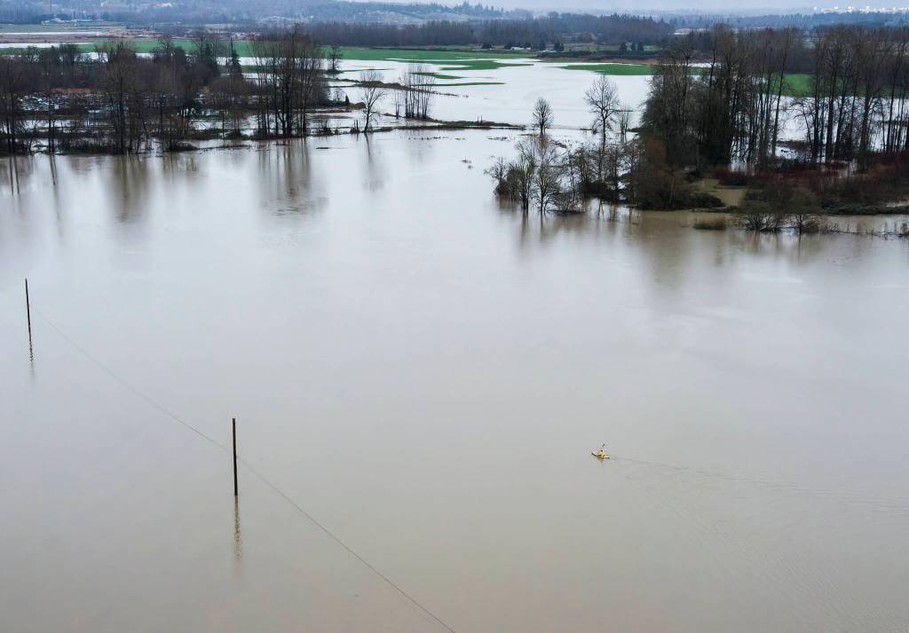 A person in a kayak paddles across flooded Stocker Fields on Thursday, Dec. 11, 2025 in Snohomish, Washington. (Olivia Vanni / The Herald)
