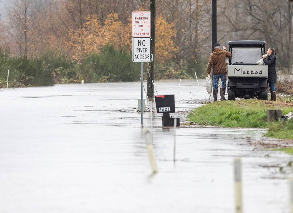 People rush to sandbag their property as the Snohomish River floods Riverview Road on Thursday, Dec. 11, 2025 in Snohomish, Washington. (Olivia Vanni / The Herald)