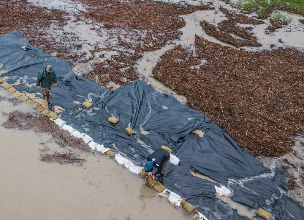 People rush to sandbag their property as the Snohomish River floods Riverview Road on Thursday, Dec. 11, 2025 in Snohomish, Washington. (Olivia Vanni / The Herald)