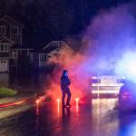 A Snohomish Police officer places flares along First Street due to water over the road on Thursday, Dec. 11, 2025 in Snohomish, Washington. (Olivia Vanni / The Herald)