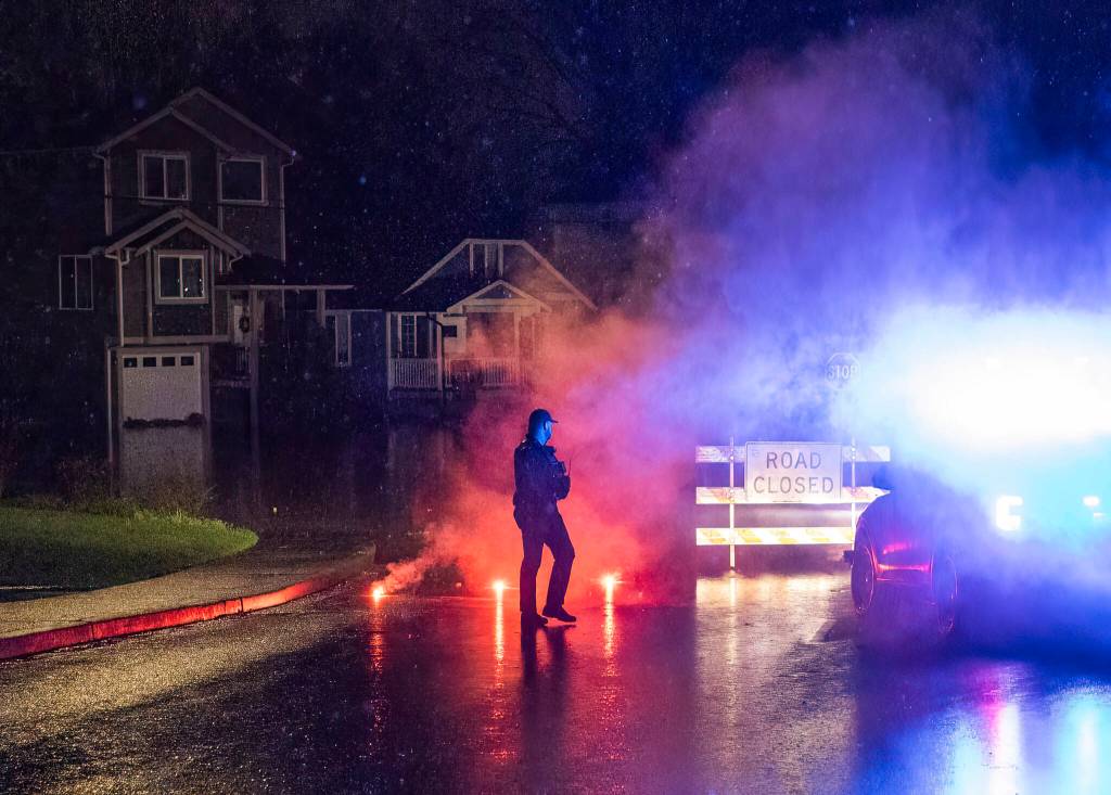 A Snohomish Police officer places flares along First Street due to water over the road on Thursday, Dec. 11, 2025 in Snohomish, Washington. (Olivia Vanni / The Herald)
