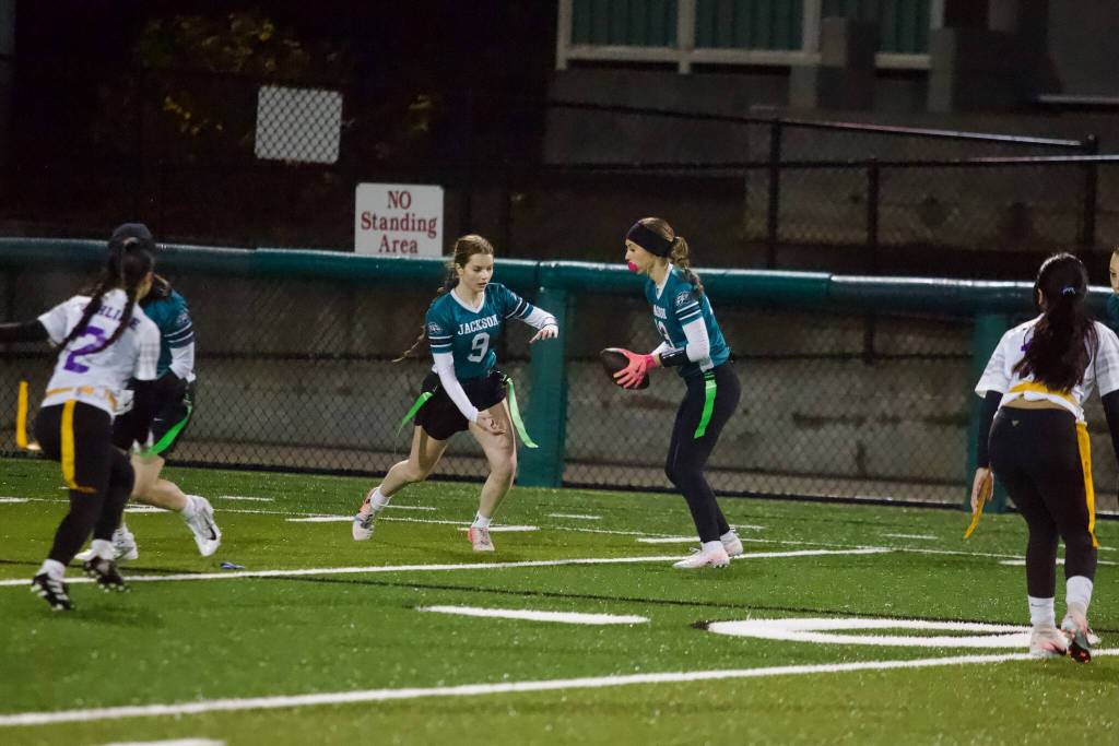 Jackson senior Eva Torres hands the ball off to junior Laila Lowery during the Timberwolves 23-7 win against Highline at Pop Keeney Stadium on Dec. 11, 2025. (Joe Pohoryles / The Herald)