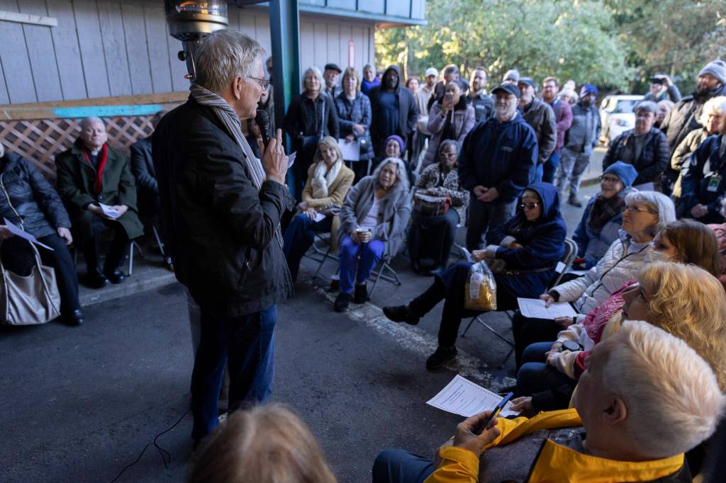 People listen as Rick Steves announces he has purchased the Jean Kim Foundation Hygiene Center property so the center can stay open on Wednesday, Dec. 17, 2025 in Lynnwood, Washington. (Olivia Vanni / The Herald)