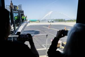 People take photos and videos as the first Frontier Arlines flight arrives at Paine Field Airport under a water cannon salute on Monday, June 2, 2025 in Everett, Washington. (Olivia Vanni / The Herald)