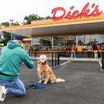 Ande Edlund takes a photograph of his dog Chase wearing a Dicks Drive-In hat before the grand opening on June 12, 2025 in Everet. (Olivia Vanni / The Herald)