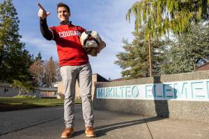 Brandon Tepley does a signature Butch pose while holding a vintage Butch head outside of his job at Mukilteo Elementary where he is dean of students on Thursday, Jan. 22, 2026 in Mukilteo, Washington. (Olivia Vanni / The Herald)