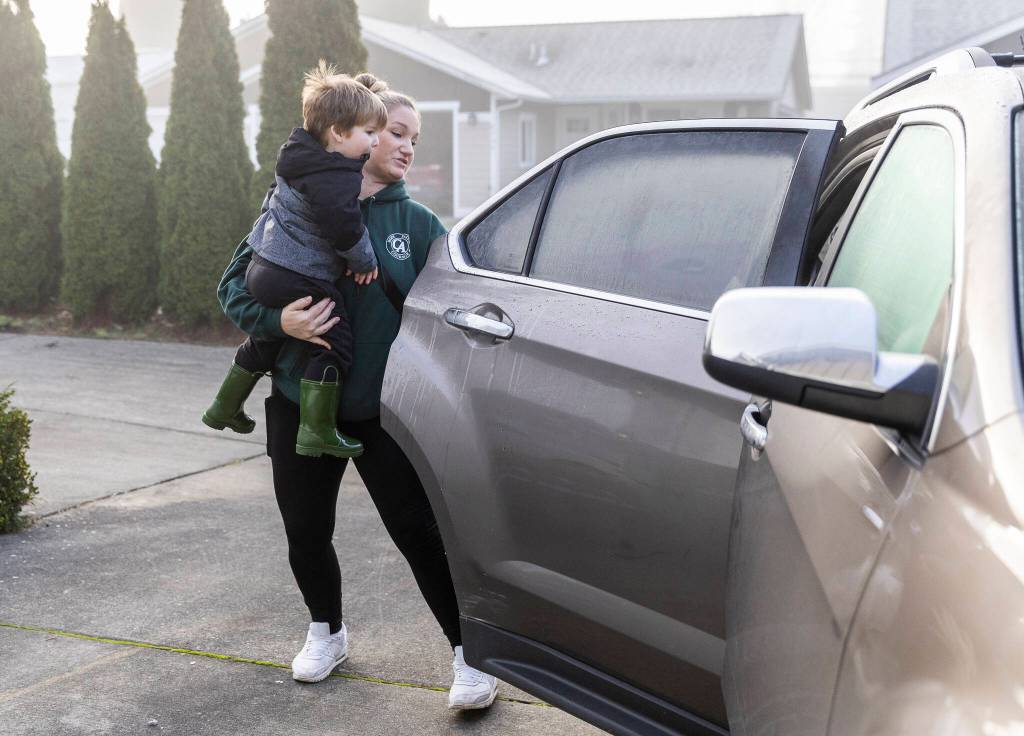 Boyle opens the car door to put Oaklen, 2, into his car seat before heading off to drop her sons at daycare on Tuesday, Dec. 30, 2025 in Marysville, Washington. (Olivia Vanni / The Herald)