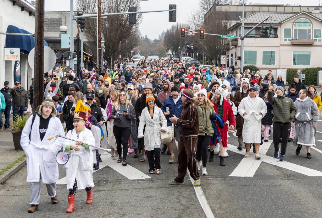 People march down Main Street making their way to Bracketts Landing North to participate in the 19th annual Polar Bear Plunge on Thursday, Jan. 1, 2026, in Edmonds, Washington. (Olivia Vanni / The Herald)