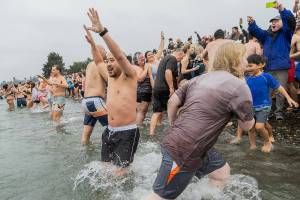 Jonni Ng runs into the water at Brackett’s Landing North during the 19th annual Polar Bear Plunge on Thursday, Jan. 1, 2026 in Edmonds, Washington. The plunge at Brackett’s Landing beach was started by Brian Taylor, the owner of Daphnes Bar. (Olivia Vanni / The Herald)