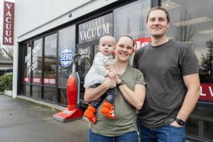 Everett Vacuum owners Kelley and Samantha Ferran with their daughter Alexandra outside of their business on Friday, Jan. 2, 2026 in Everett, Washington. (Olivia Vanni / The Herald)