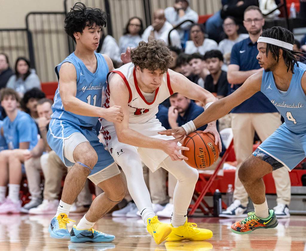 Snohomishs Grady Rohrich tries to keep possession of the ball while Meadowdales Nolan Lee and Hasaan Motley defend during the game on Monday, Jan. 5, 2026 in Snohomish, Washington. (Olivia Vanni / The Herald)