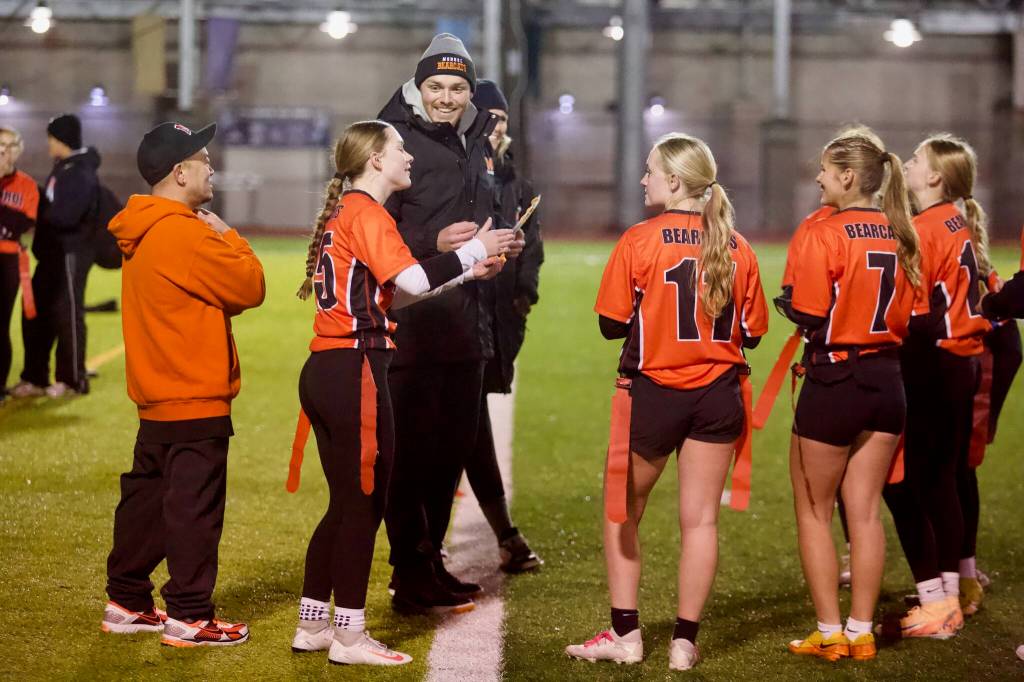 Monroe girls flag football coach Connor Wood (center) speaks to a group of players during a timeout at Everett Memorial Stadium on Jan. 7, 2026. (Joe Pohoryles / The Herald)