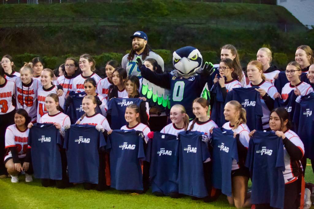 Former Seattle Seahawks offensive lineman Garry Gilliam and Seahawks mascot Blitz pose with the Monroe girls flag football team at Everett Memorial Stadium on Jan. 7, 2026. (Joe Pohoryles / The Herald)