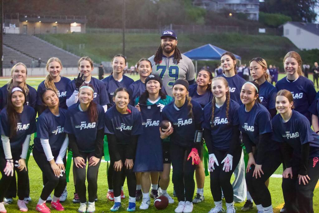 Former Seattle Seahawks offensive lineman Garry Gilliam poses with the Jackson girls flag football team at Everett Memorial Stadium on Jan. 7, 2026. (Joe Pohoryles / The Herald)