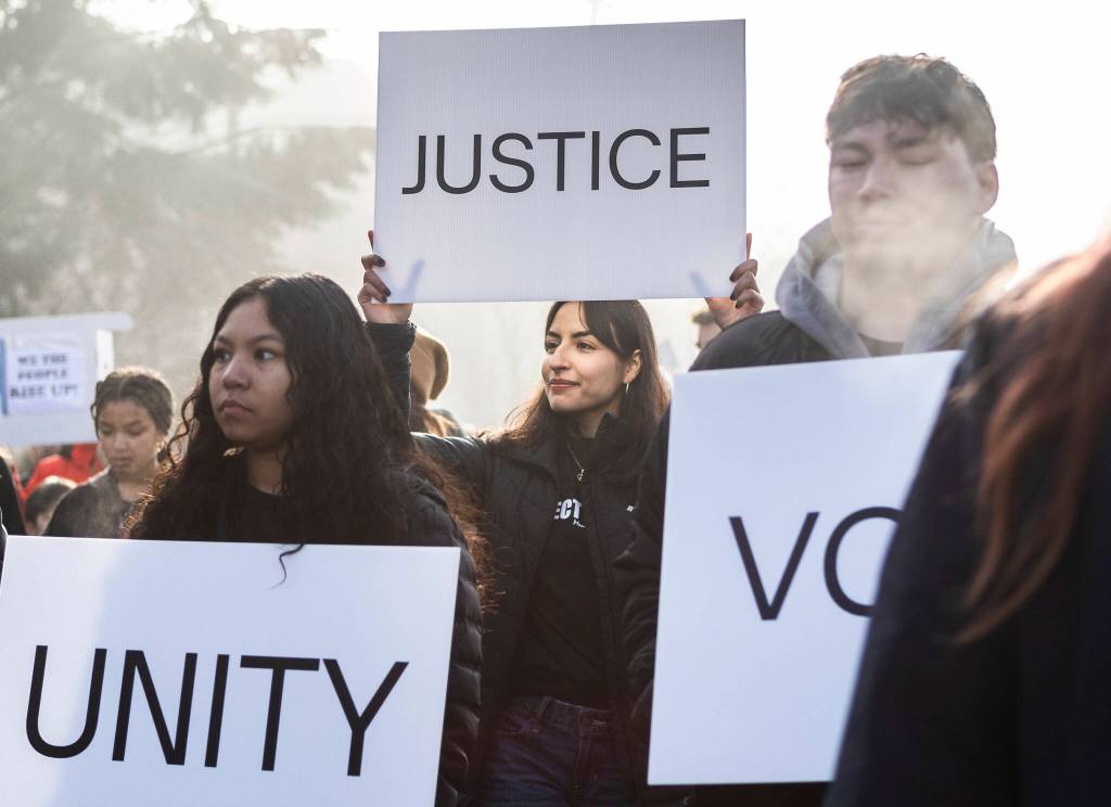 Karolyna Garcia holds a sign that says justice while she walks in a Martin Luther King Jr. Day march on Monday, Jan. 19, 2026, in Everett, Washington. (Olivia Vanni / The Herald)