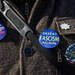 A person wears pins during during South Snohomish County Indivisibles Signs of Fascism protest on Tuesday, Jan. 20, 2026 in Edmonds, Washington. (Olivia Vanni / The Herald)