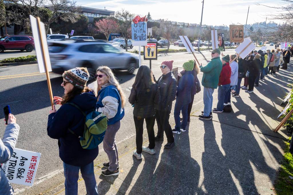 Cars drive past hundreds participating in South Snohomish County Indivisibles Signs of Fascism protest on Tuesday, Jan. 20, 2026 in Edmonds, Washington. (Olivia Vanni / The Herald)