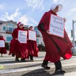 Shelly Ehni, with Edmonds United Methodist, crosses Sunset Avenue while holding a sign during South Snohomish County Indivisibles Signs of Fascism protest on Tuesday, Jan. 20, 2026 in Edmonds, Washington. (Olivia Vanni / The Herald)