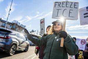 Barbara and Anne Guthrie holds signs and wave at cars offloading from the ferry during South Snohomish County Indivisible’s Signs of Fascism protest on Tuesday, Jan. 20, 2026 in Edmonds, Washington. (Olivia Vanni / The Herald)