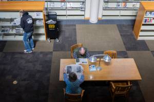 People read newspapers from the library selection at the Everett Public Library on Thursday, April 3, 2025 in Everett, Washington. (Olivia Vanni / The Herald)