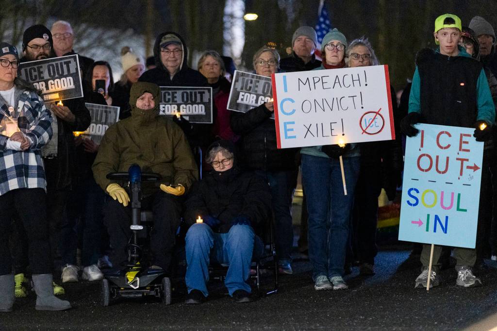 People hold signs during a vigil held at the Snohomish County Campus as a show of solidarity with the city of Minneapolis as the Midwest city faces a dramatic uptick in immigration enforcement on Tuesday, Jan. 27, 2026, in Everett, Washington. (Olivia Vanni / The Herald)
