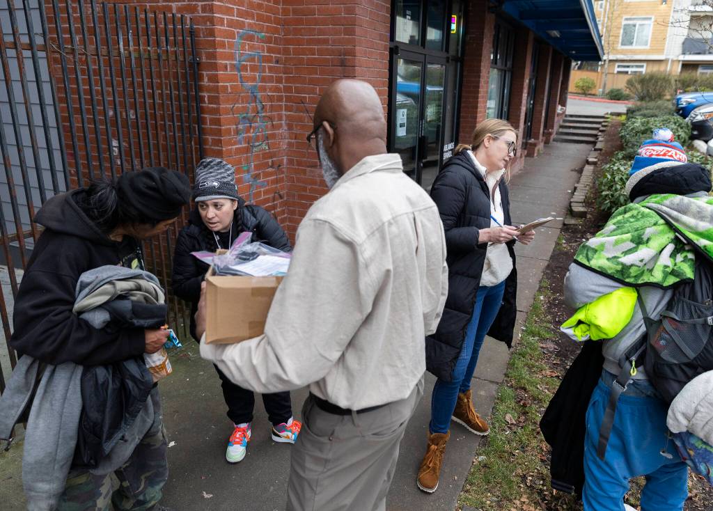 Rachel McGee, Toni Gardner and Jobe Momodou ask individuals questions for the Point In Time count survey on Tuesday, Jan. 27, 2026, in Everett, Washington. (Olivia Vanni / The Herald)
