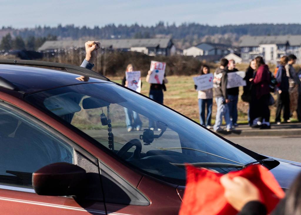 A driver puts a fist in the air while driving past a student walkout and protest on Thursday, Feb. 5, 2026 in Marysville, Washington. (Olivia Vanni / The Herald)