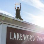 Anayah Ulrich holds a sign while standing on top of the Lakewood Crossing entrance sign during a student walkout and protest on Thursday, Feb. 5, 2026 in Marysville, Washington. (Olivia Vanni / The Herald)