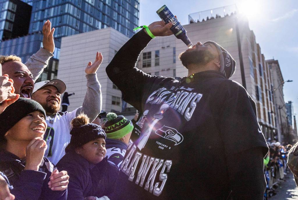 A Seahawks player is cheered on by fans as he chugs a beer during the Seahawks World Champions Parade on Wednesday, Feb. 11, 2026 in Seattle, Washington. (Olivia Vanni / The Herald)