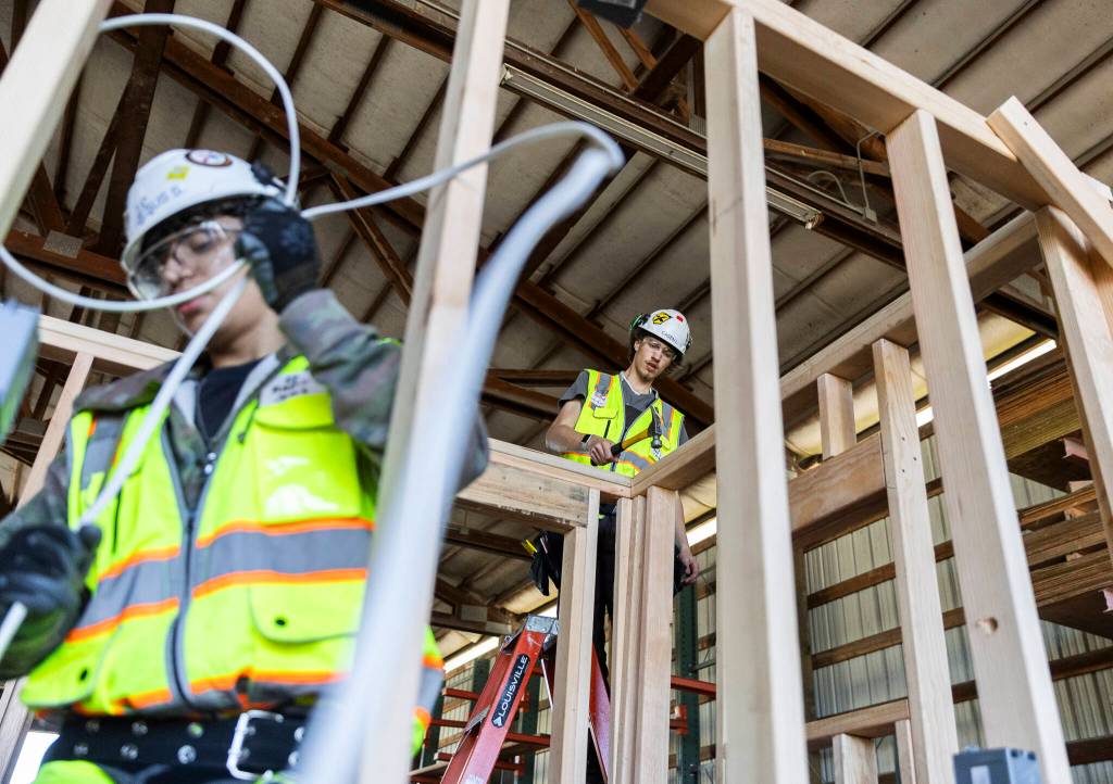 Jesus Solorzano, left, threads wire while Casey Lanting, right, finishes wall framing on Tuesday, Feb. 10, 2026 in Marysville, Washington. (Olivia Vanni / The Herald)