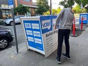 A voter puts a ballot in the drop box at the Ballard branch of the Seattle Public Library in King County in August 2024. This voting location is one of the most popular in the county. (Laurel Demkovich/Washington State Standard)