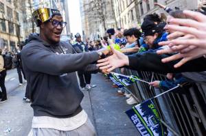 Seattle Seahawks’ Kenneth Walker III and Super Bowl MVP high fives fans lined up along 4th Avenue during the Seahawks World Champions Parade on Wednesday, Feb. 11, 2026 in Seattle, Washington. (Olivia Vanni / The Herald)