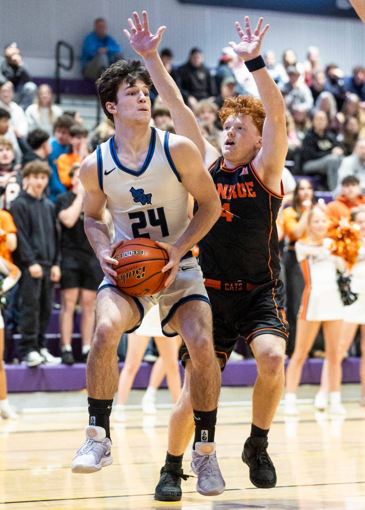 Shorewoods Jaden Marlow jumps trying to pass the ball while Monroes Tate Hammerquist defends during the 3A state opening round loser-out game on Friday, Feb. 27, 2026 in Bothell, Washington. (Olivia Vanni / The Herald)