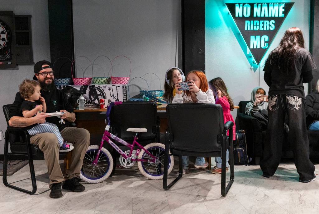 Dan Tapeworm Caldwell hold his daughter Willow while other kids play games and listen to music on March 12, 2026, in Everett. (Olivia Vanni / The Herald)