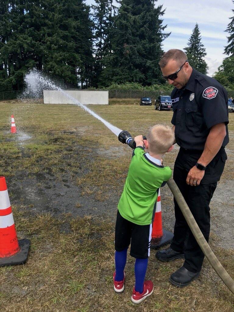 Everett Fire Captain D.J. Neyens works with a Lowell Elementary School student during a field day event. (Photo courtesy of D.J. Neyens)