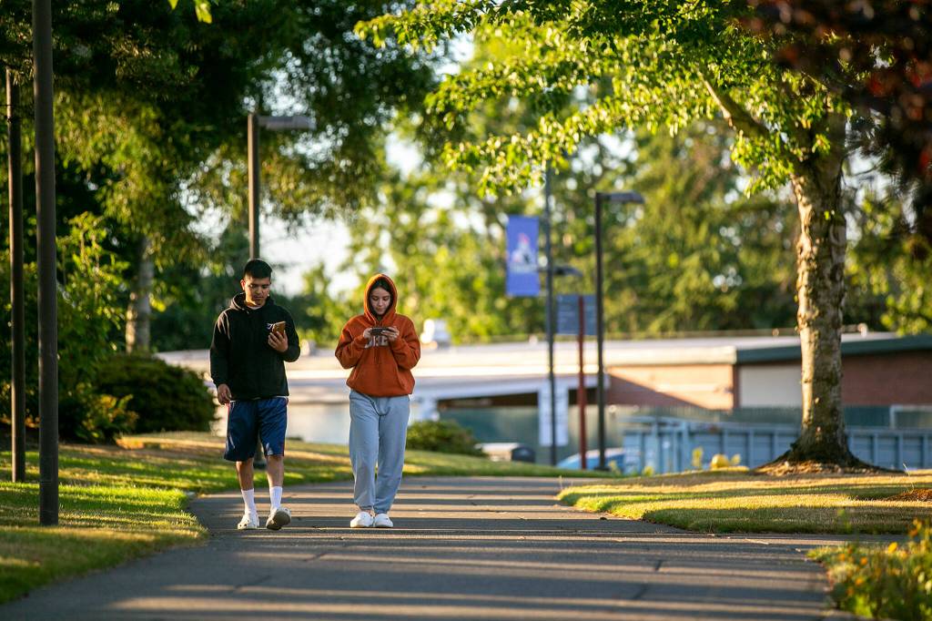 Two students walk along a path through campus in 2022 at Everett Community College in Everett. A proposed $14 million statewide cut to Running Start would amount to a $200,000 to $300,000 budget reduction at Everett Community College, limiting the number of classes the college can pay for per student. (Ryan Berry / The Herald)