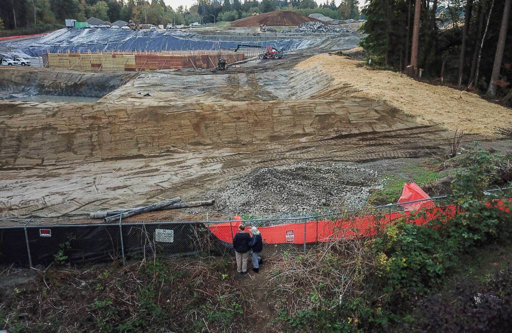 Two people look south toward the Eastview development site through a fence dividing the site from the end of 79th Avenue Southeast on Thursday, Oct. 16, 2026 in Snohomish, Washington. (Olivia Vanni / The Herald)