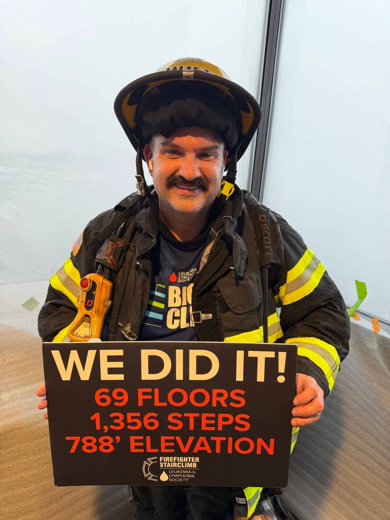 Herald writer Aaron Coe holds a sign after walking up the staircase to the 73rd floor of the Columbia Tower at the Blood Cancer Uniteds Firefighter Stairclimb on Sunday in Seattle. (Photo courtesy of Aaron Coe)
