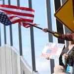 Josiah Morgan, of Snohomish, holds an upside-down American flag during a No Kings Day rally along Broadway on Saturday in Everett. (Mike Henneke / The Herald)