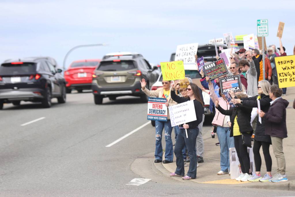 Protesters wave to passing motorists along Broadway during a No Kings Day rally on Saturday in Everett. (Michael Henneke / The Herald)