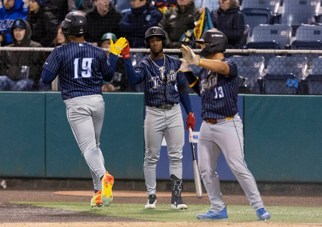 Randy De Jesus (19) of the Tri-City Dust Devils high-fives teammates after scoring the 13th run for the Tri-City Dust Devils in the fourth inning against the Everett AquaSox on Tuesday, April 7, 2026 in Everett, Washington. (Olivia Vanni / The Herald)