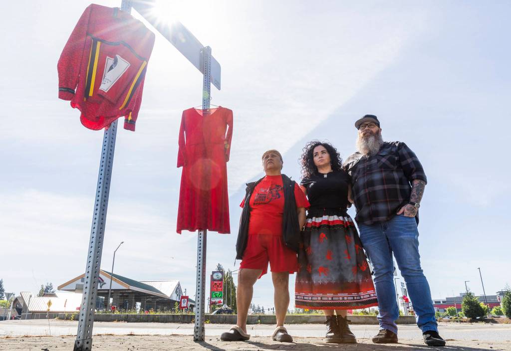 Monie Ordonia, left to right, Skaweets Sarah Hart, and Anthony Hart stand next to a Missing and Murdered Indigenous People display they have organized and curated to create awareness for those who are currently missing or have been murdered on Monday, May 4, 2026 in Tulalip, Washington. (Olivia Vanni / The Herald)