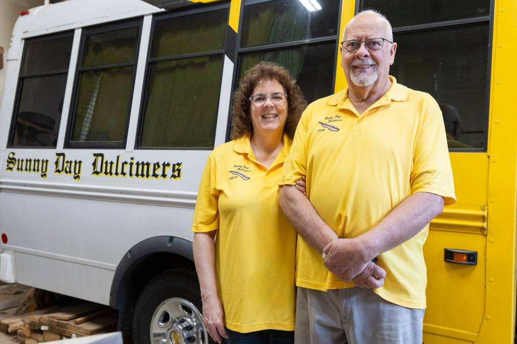 Teresa Ellis and John Ellis next to their Sunny Days Dulcimers van they bring with them to festivals on Thursday, May 7, 2026 in Arlington, Washington. (Olivia Vanni / The Herald)