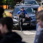 Bothell High Schools school resource officer Officer Garrett Ware watches as students walk out of the high school in protest of the school boards vote to not renew the contract for his position at the school on Monday, May 18, 2026, in Bothell, Washington. (Olivia Vanni / The Herald)