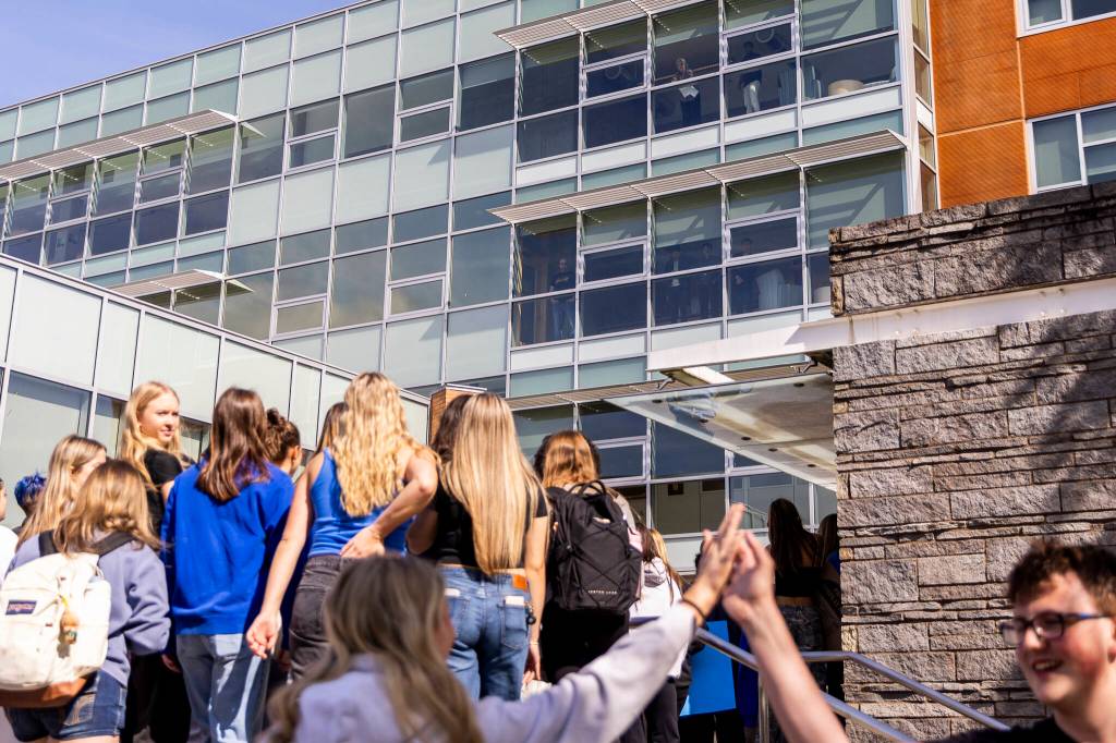 People inside Bothell City Hall look out over the crowd of Bothell High School students and other community members protesting the school boards vote to not renew the contract for the high schools school resource officer on Monday, May 18, 2026, in Bothell, Washington. (Olivia Vanni / The Herald)