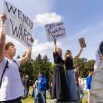 Stefan Krzeszowski, left to right, Quinn Hall and Olivia Santoro hold signs along Bothell Way in protest of the school boards vote to not renew the contract for Bothell High Schools school resource officer on Monday, May 18, 2026, in Bothell, Washington. (Olivia Vanni / The Herald)