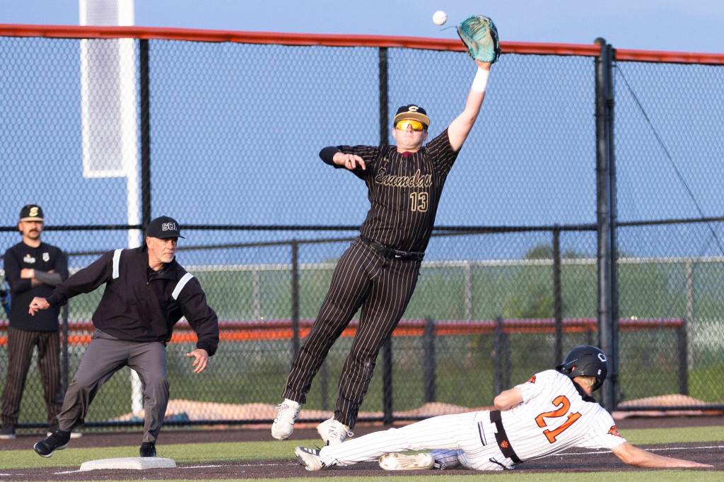 Monroes Gavin Prescott slides safely into third base while Enumclaws jumps to catch a throw during the 3A state opening round loser-out game on Tuesday, May 19, 2026 in Monroe, Washington. (Olivia Vanni / The Herald)
