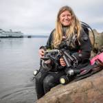 Annie Crawley poses for a photo with her scuba gear at Brackett’s Landing near the Port of Edmonds on Saturday, Feb. 3, 2024 in Edmonds, Washington. (Annie Barker / The Herald)